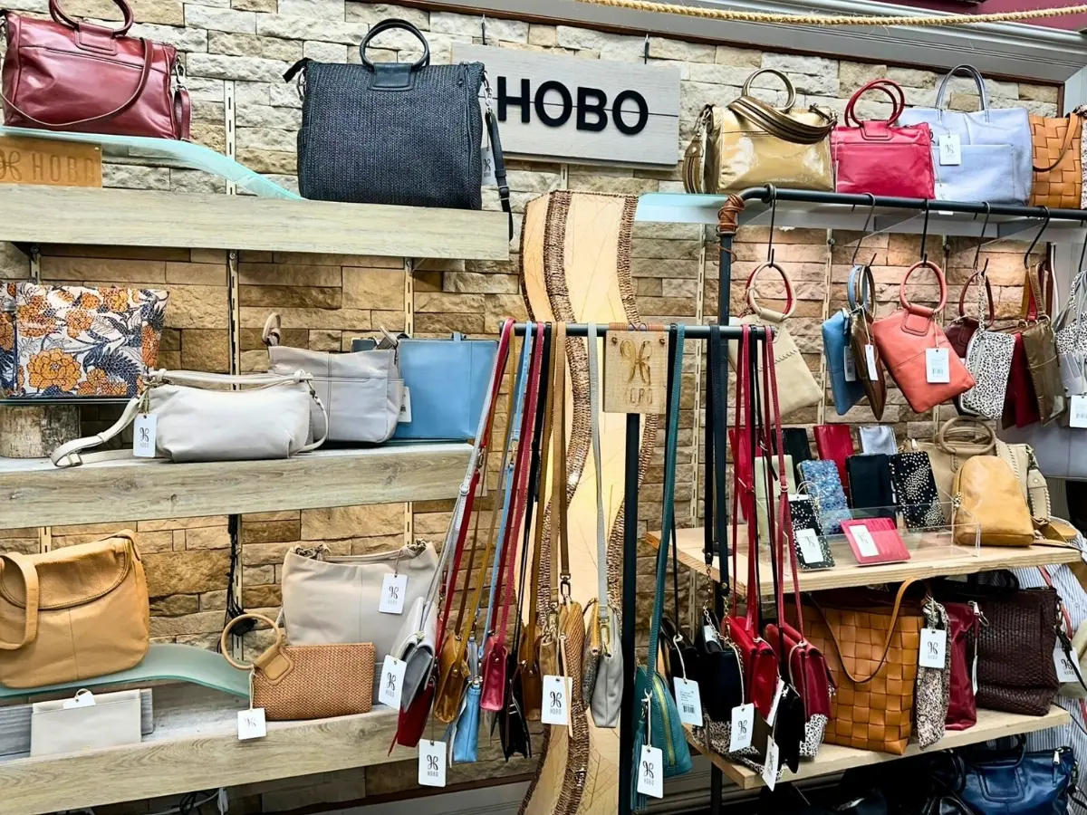 An assortment of handbags and belts displayed on shelves in a retail store.