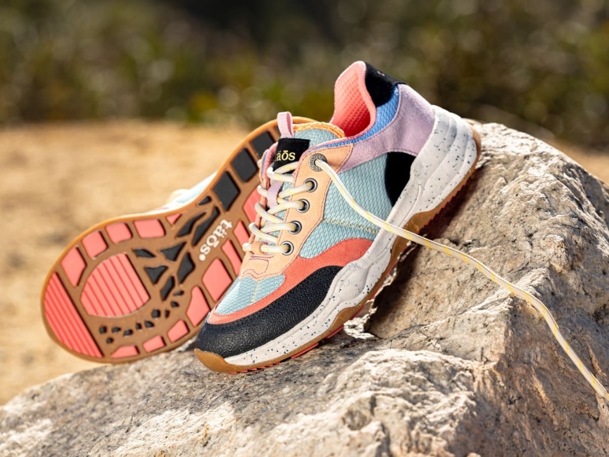 A pair of colorful trail running shoes placed on a rocky surface outdoors.