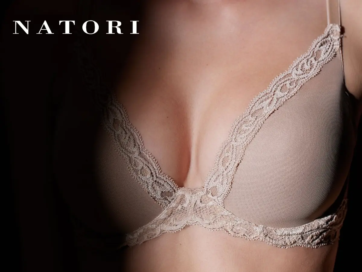 A close-up of a woman wearing a beige lace bra with the brand name "natori" displayed in the upper left corner.